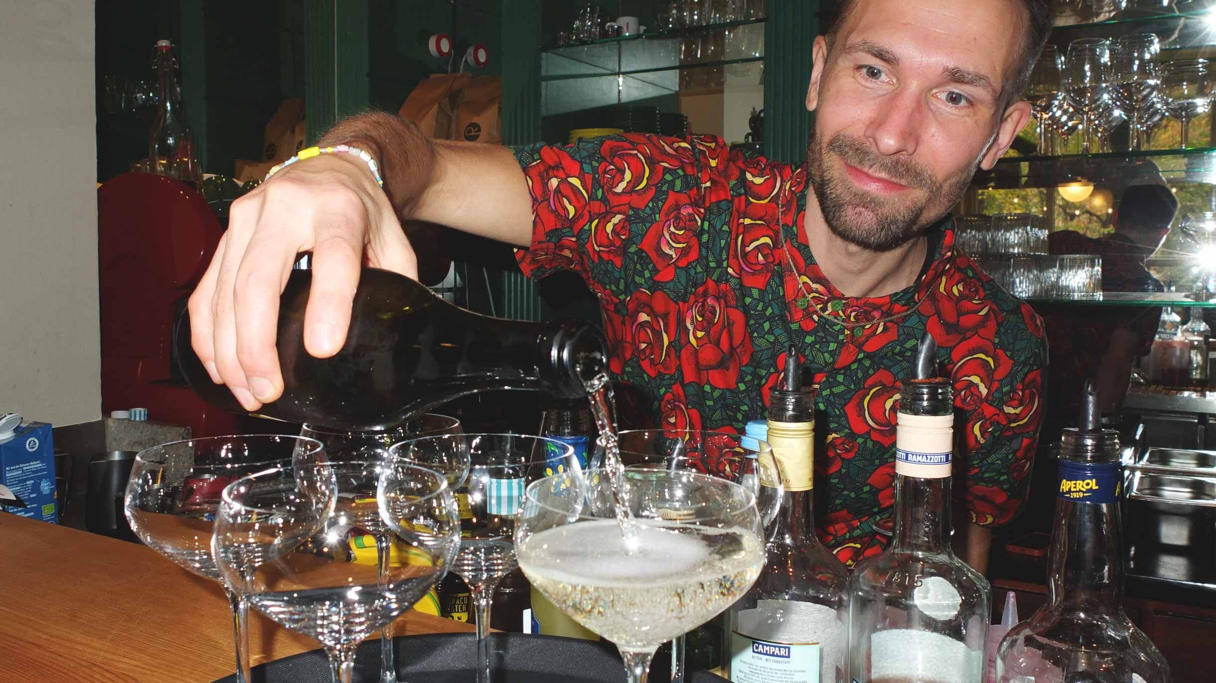 Max schenkt Champagner hinter der Bar ein